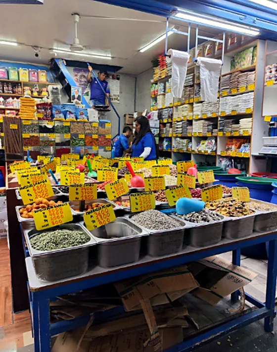 Local de venta a granel con bandejas de especias, legumbres y frutos secos con precios en cartulinas amarillas